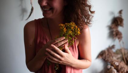 Jowita, jedna z autorek Blogrodu, uśmiecha się, trzymając w dłoniach bukiet dziurawca.