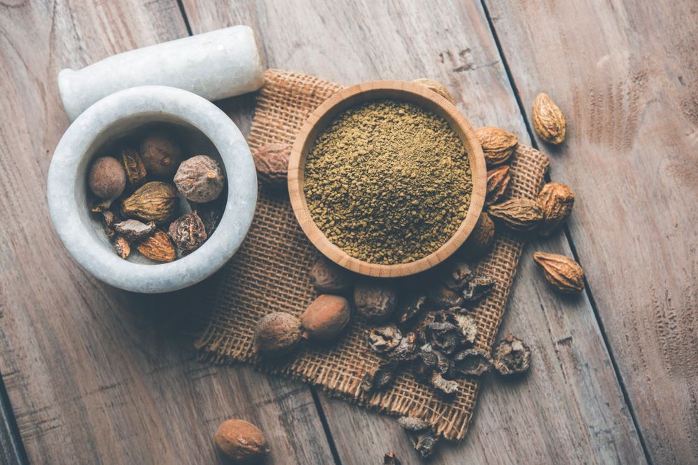 Orzechy w moździerzu, obok miseczka z triphalą.